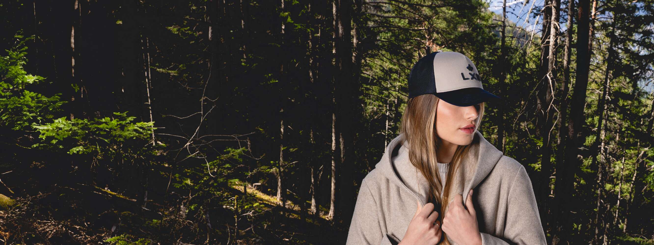 Femme portant une casquette trucker blanche assise près de la mer avec un vêtement jaune