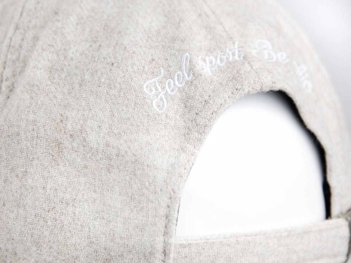 Détail de la broderie blanche Feel sport Be chic en script anglaise sur la calotte arrière du béret feutrine LXH blanc cassé