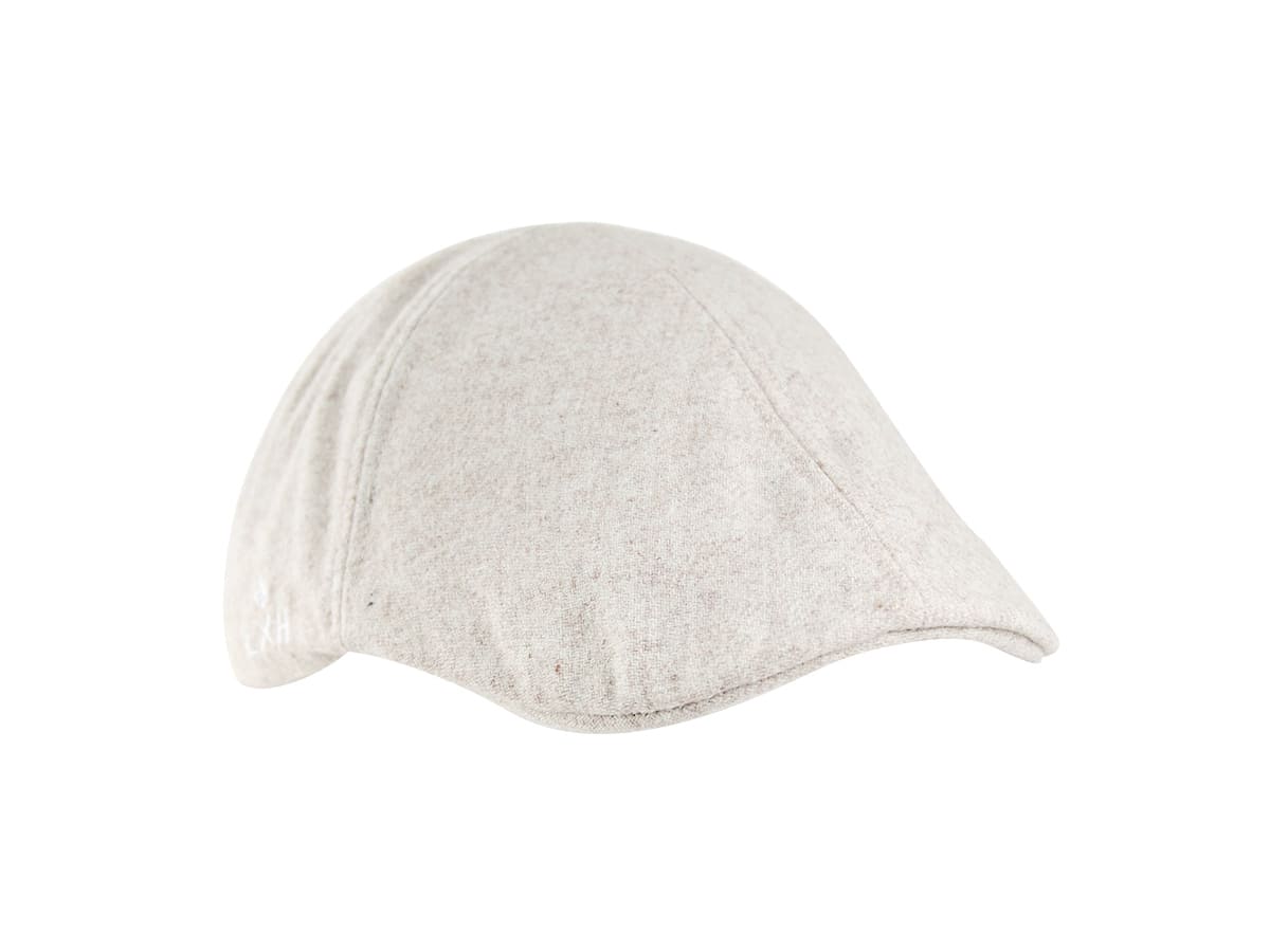 Vue trois quarts plongeante béret feutrine blanc cassé LXH, calotte structurée, coutures rayonnantes, visière incurvée.