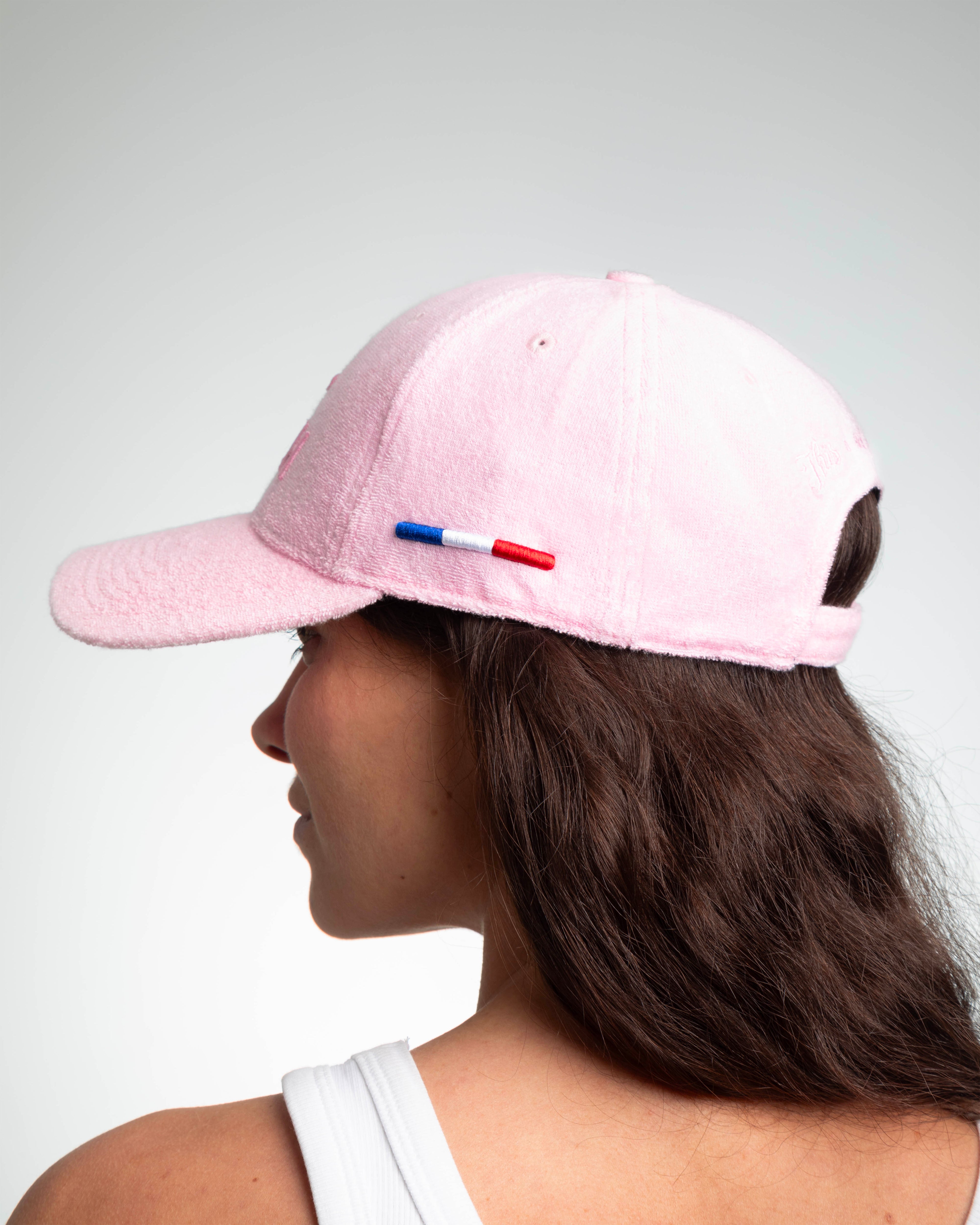 Vue de dos d'une femme portant casquette LXH éponge rose pâle, languette tricolore brodée et sangle réglable arrière.