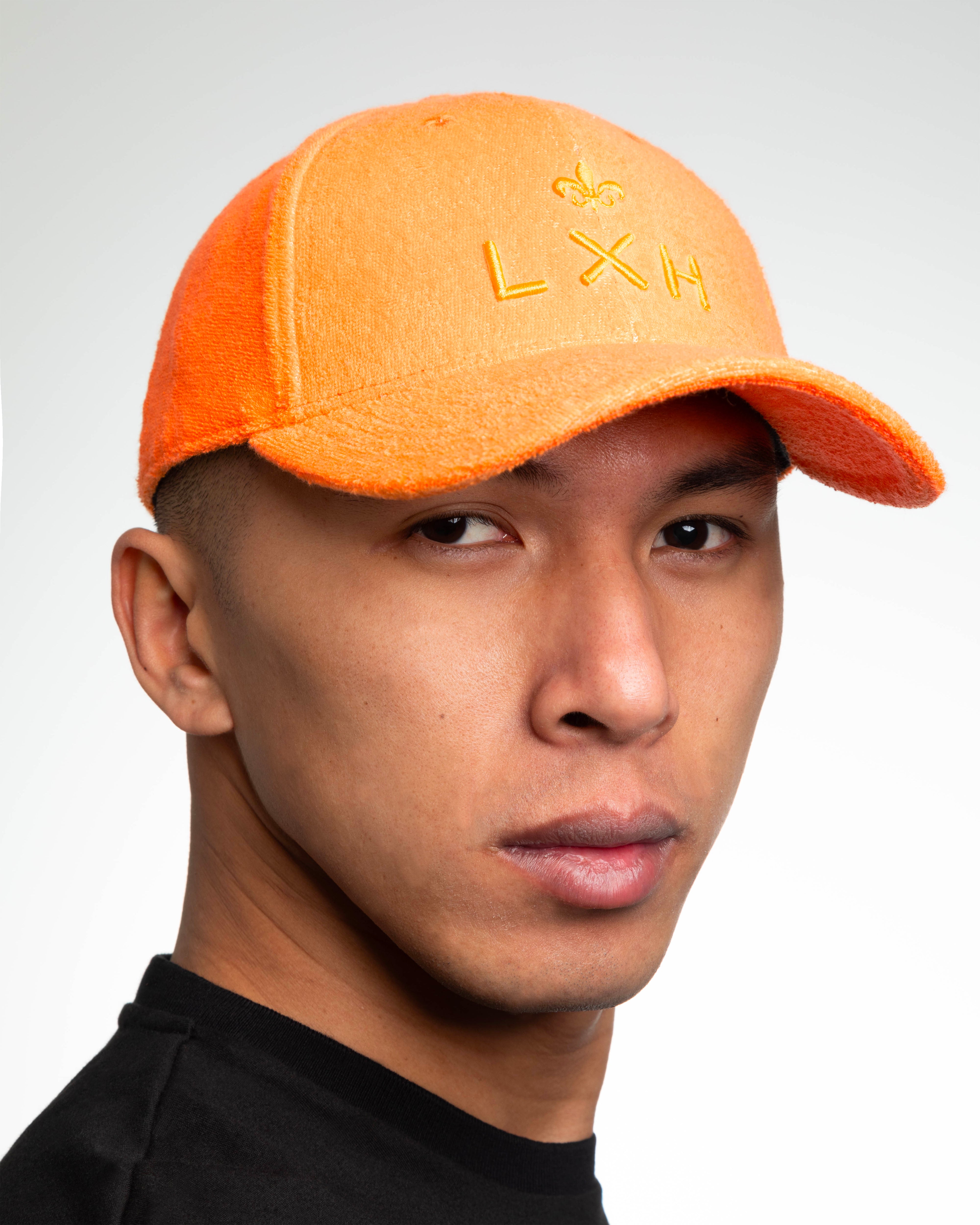 Casquette Héritage éponge orange portée de face, broderie 3D fleur de lys et LXH ton sur ton sur tissu bouclette doux