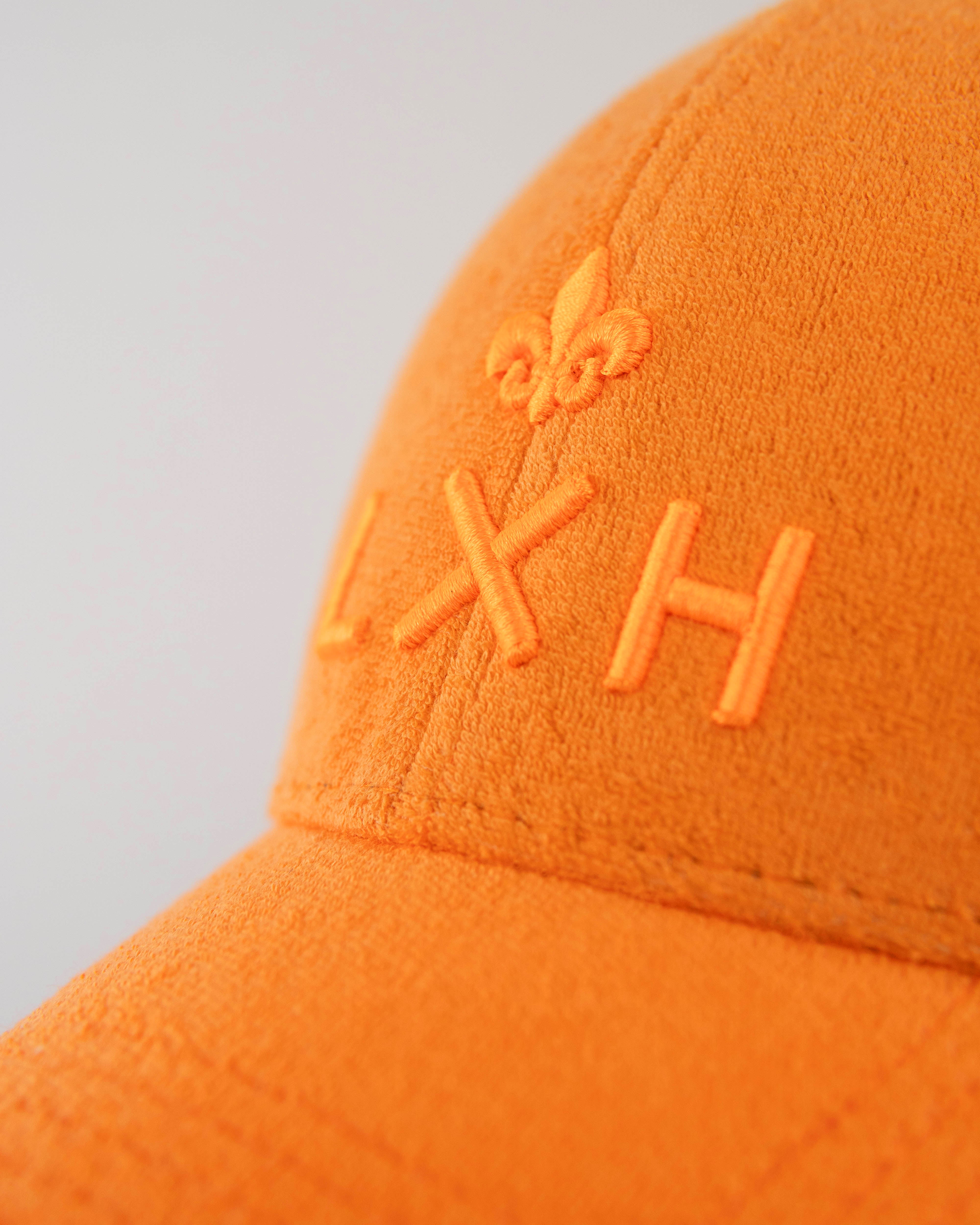 Macro broderie 3D fleur de lys et logo LXH ton sur ton sur la face avant de la casquette Héritage éponge orange.