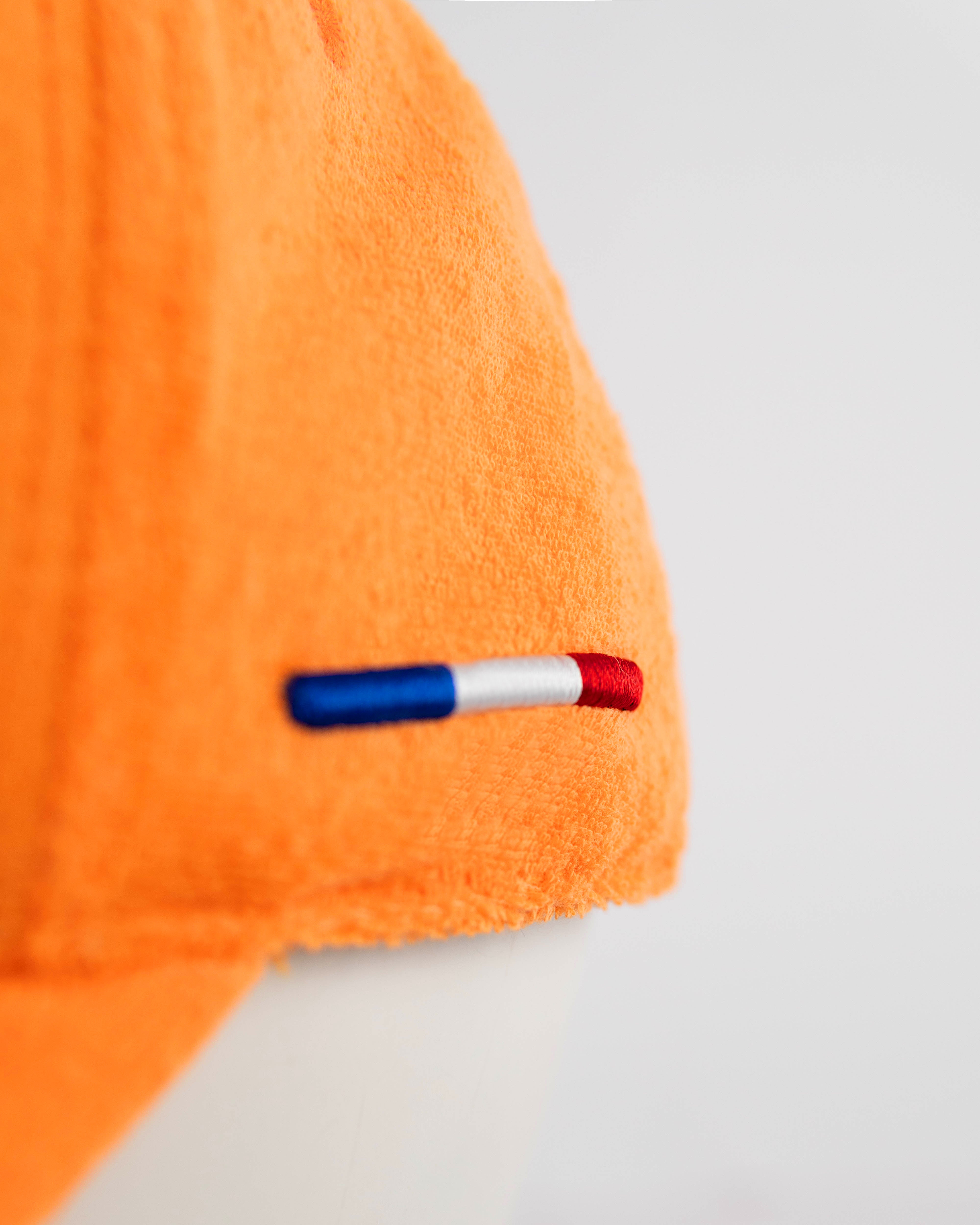 Détail du liseré tricolore bleu blanc rouge cousu sur le côté gauche de la casquette Héritage éponge orange LXH.