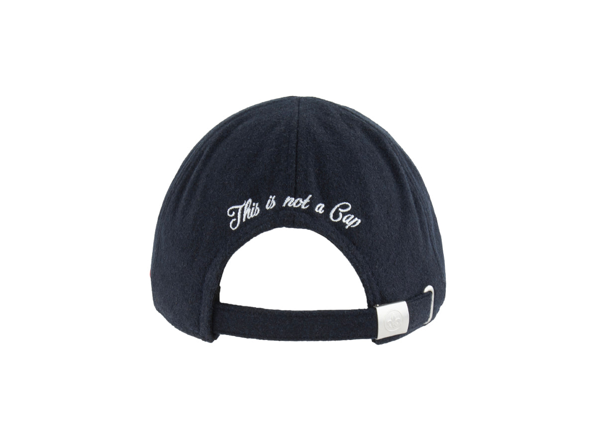 Arrière du béret plat LXH bleu nuit avec broderie blanche This is not a Cap et boucle métallique fleur de lys