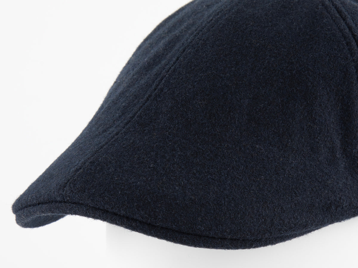 Gros plan macro sur la visière courte et la texture feutrine de laine bleu nuit chinée du béret plat LXH