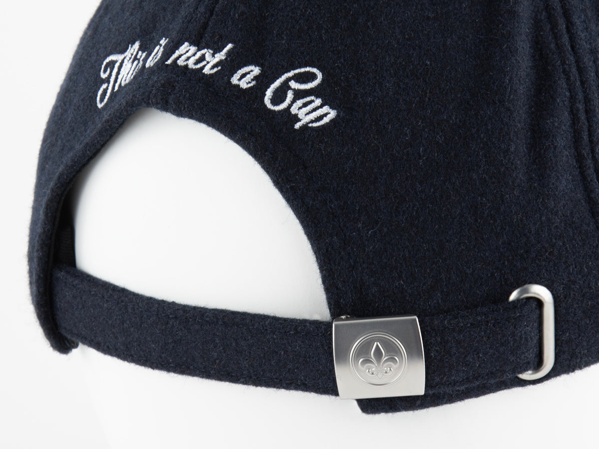 Gros plan arrière du béret bleu nuit LXH avec broderie This is not a Cap et boucle fleur de lys gravée