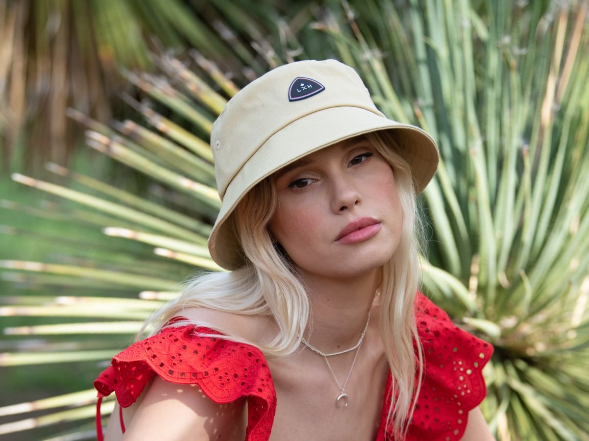Femme portant un Bob Coton Jaune Sable avec un logo élégant, parfait pour les journées ensoleillées.