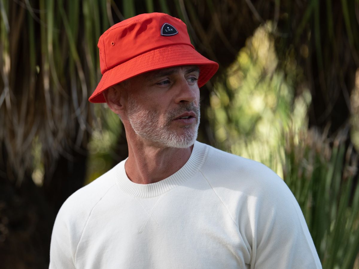 Bob Nylon Rouge de LXH porté par un homme avec un pull blanc dans un environnement naturel