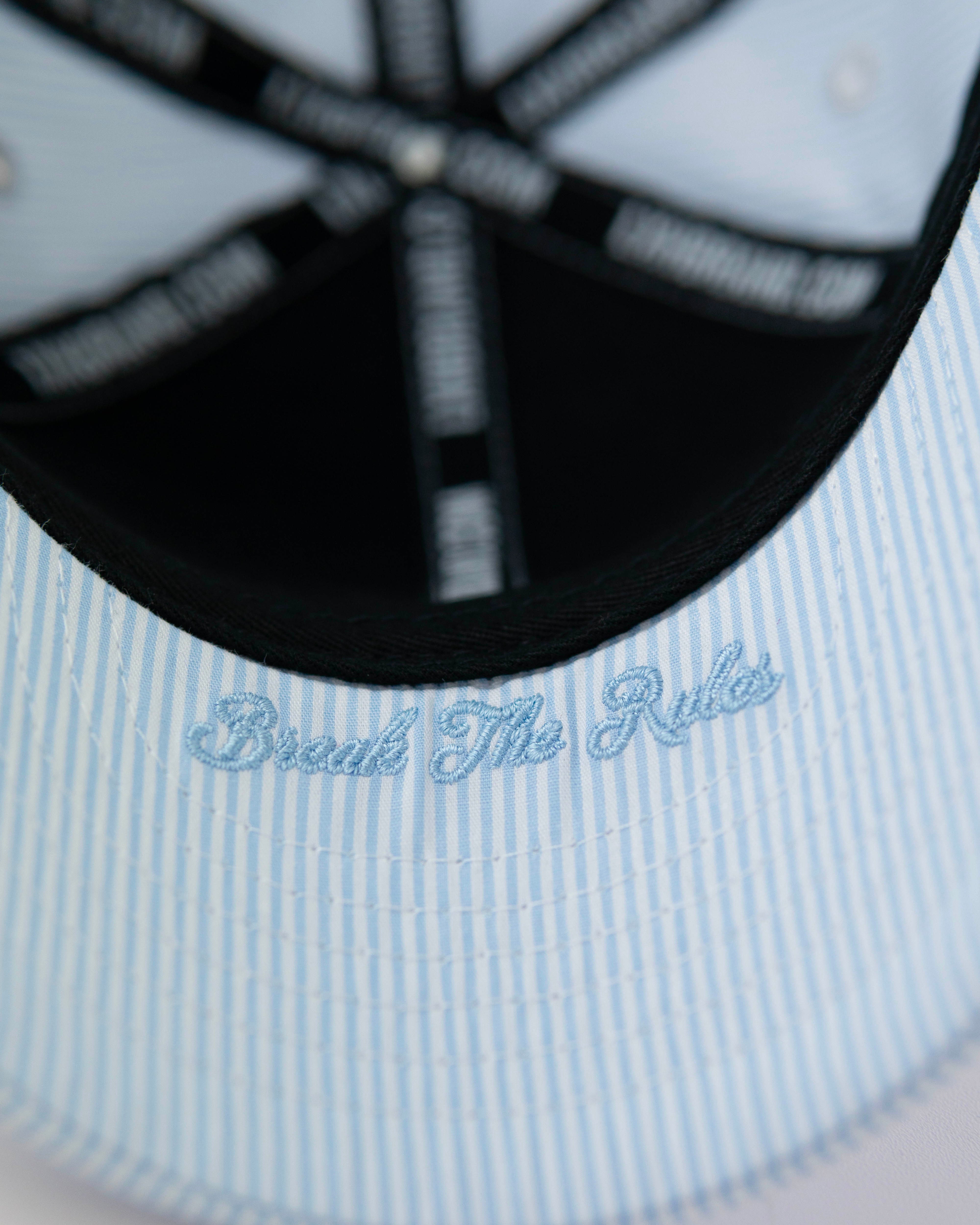 Casquette bébé rayée bleu de la marque LXH avec inscription 'Break The Rules' à l'intérieur