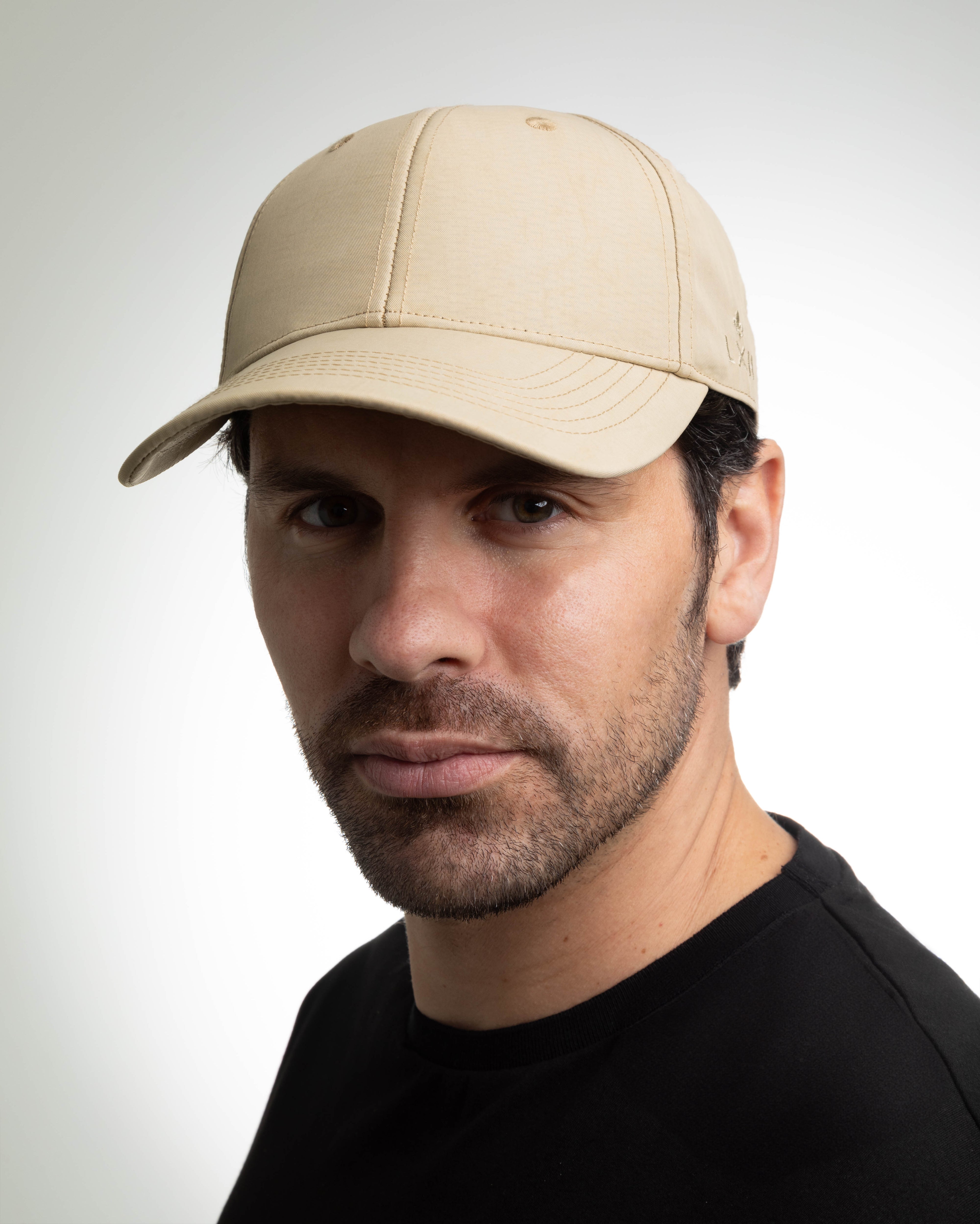 Casquette beige LXH en nylon portée par un homme avec un t-shirt noir élégante et décontractée