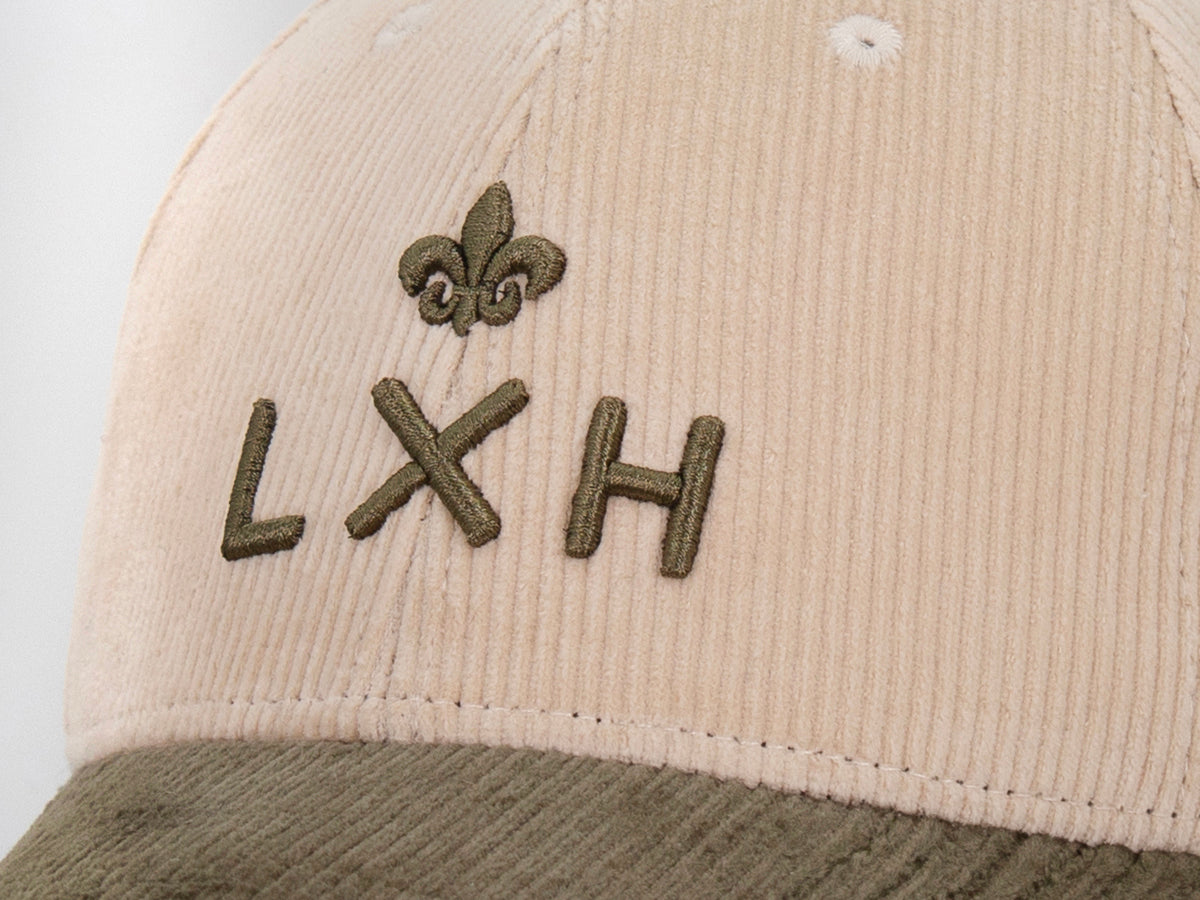 Macro panneau frontal beige, broderie en relief monogramme LXH et fleur de lys vert olive sur velours côtelé.