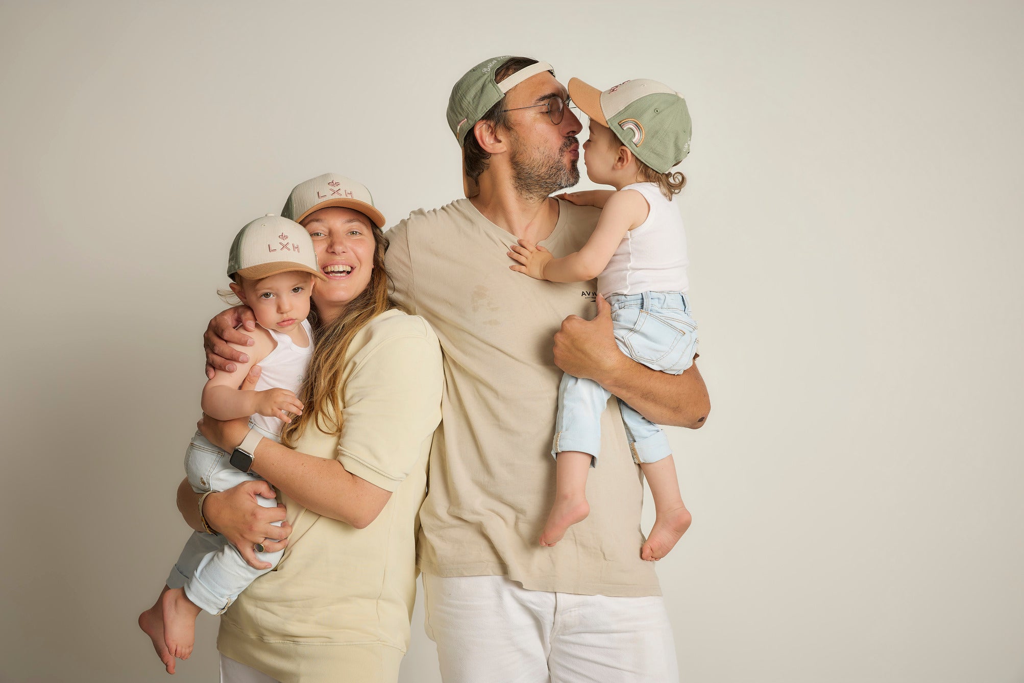 Famille portant des casquettes LXH souriant ensemble dans un décor neutre