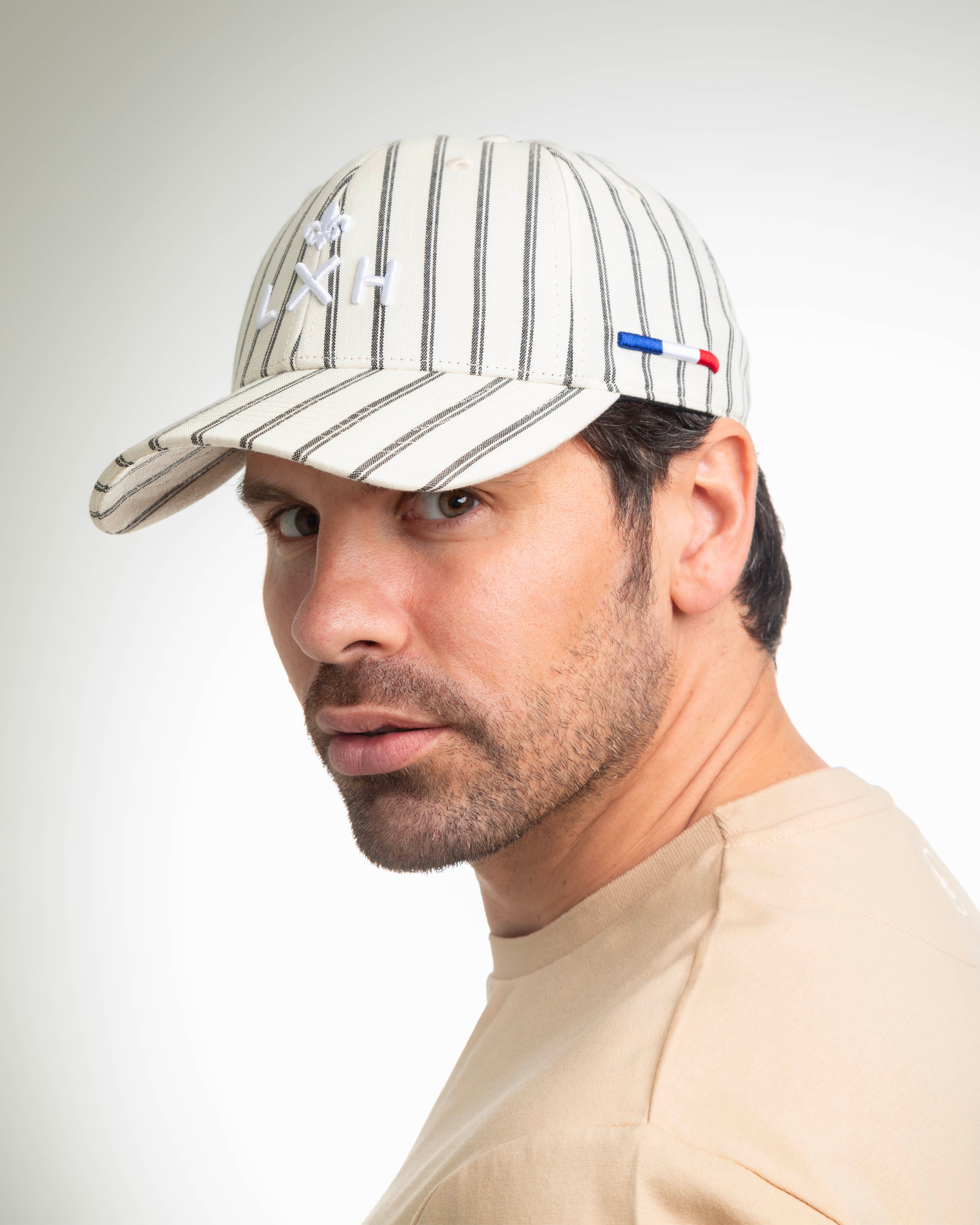 Homme portant une casquette rayée beige homme de la marque LXH avec logo brodé