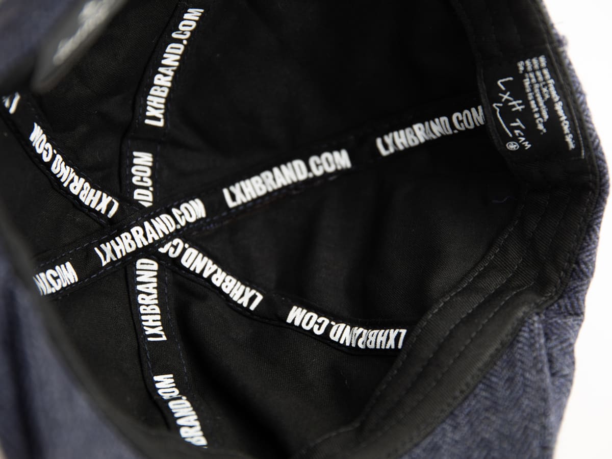 Gros plan de l'intérieur du béret LXH avec sangles noires sérigraphiées LXHBRAND.COM et étiquette LXH Team cousue.