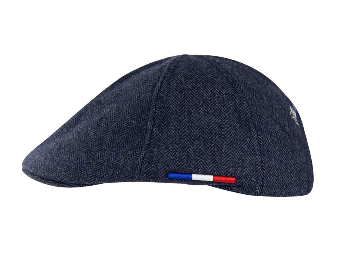 Profil droit du béret plat chevron bleu marine LXH, étiquette drapeau français visible au-dessus de la visière courte.