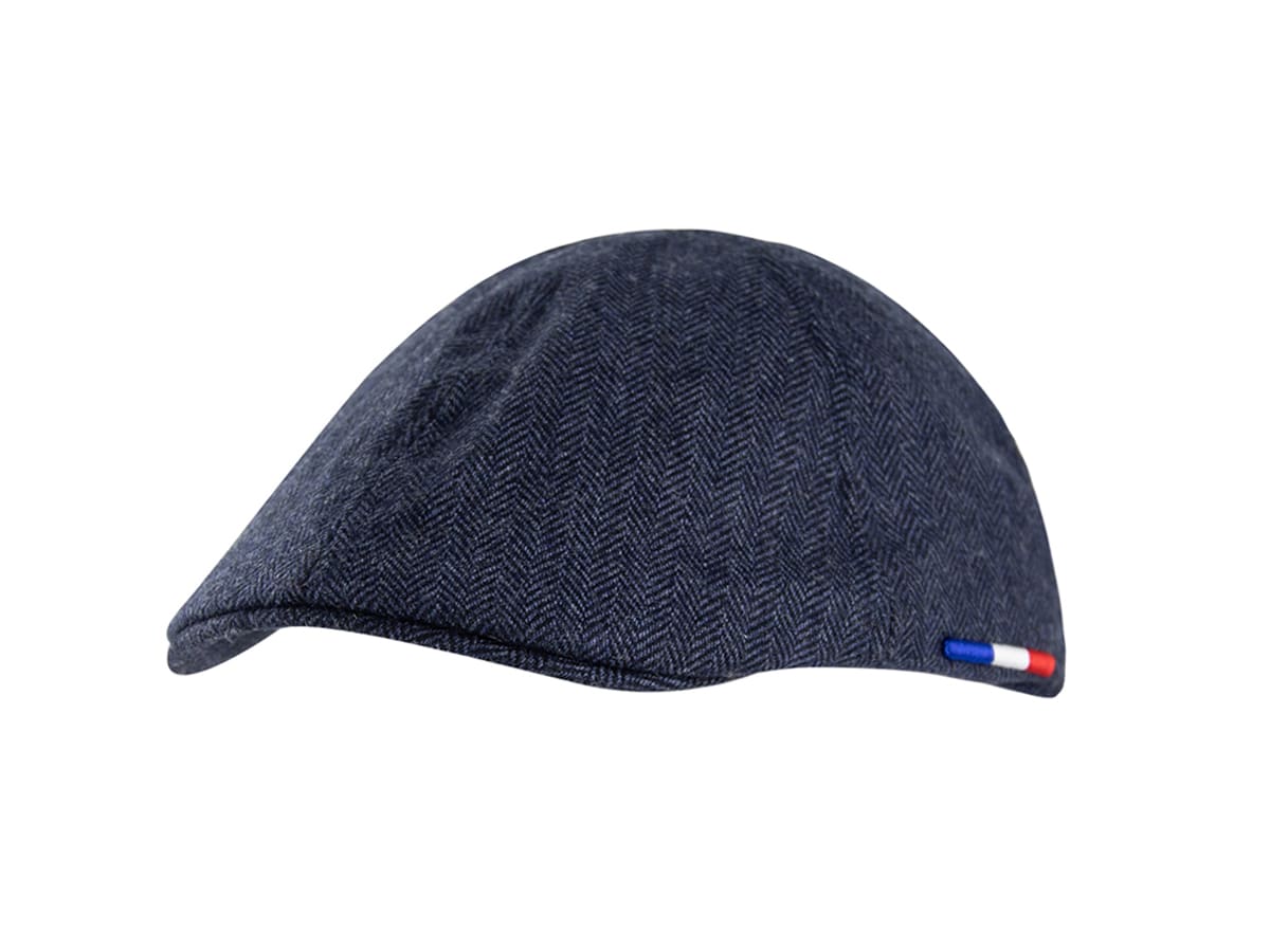 Béret plat LXH bleu marine en tissu chevron, vue profil gauche avec petite étiquette tricolore bleu blanc rouge sur le côté.