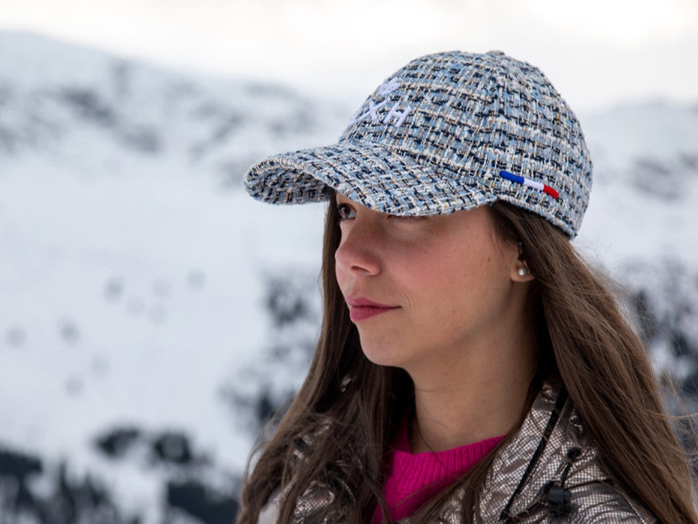 Casquette LXH Tweed Bleu Nuit portée par une femme avec un paysage de montagne enneigée en arrière-plan
