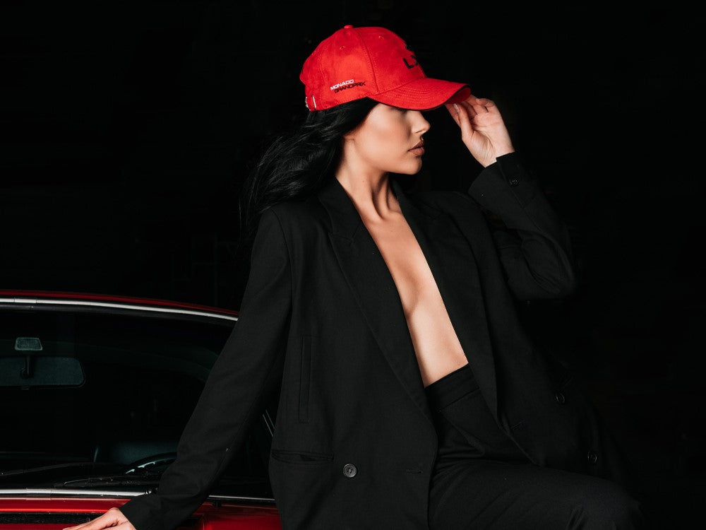 Casquette rouge LXH Monaco GP portée par une femme avec un blazer noir près d'une voiture rouge