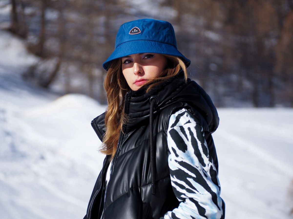 Femme portant un Bob Nylon Bleu Canard avec une veste sans manches en hiver dans la neige