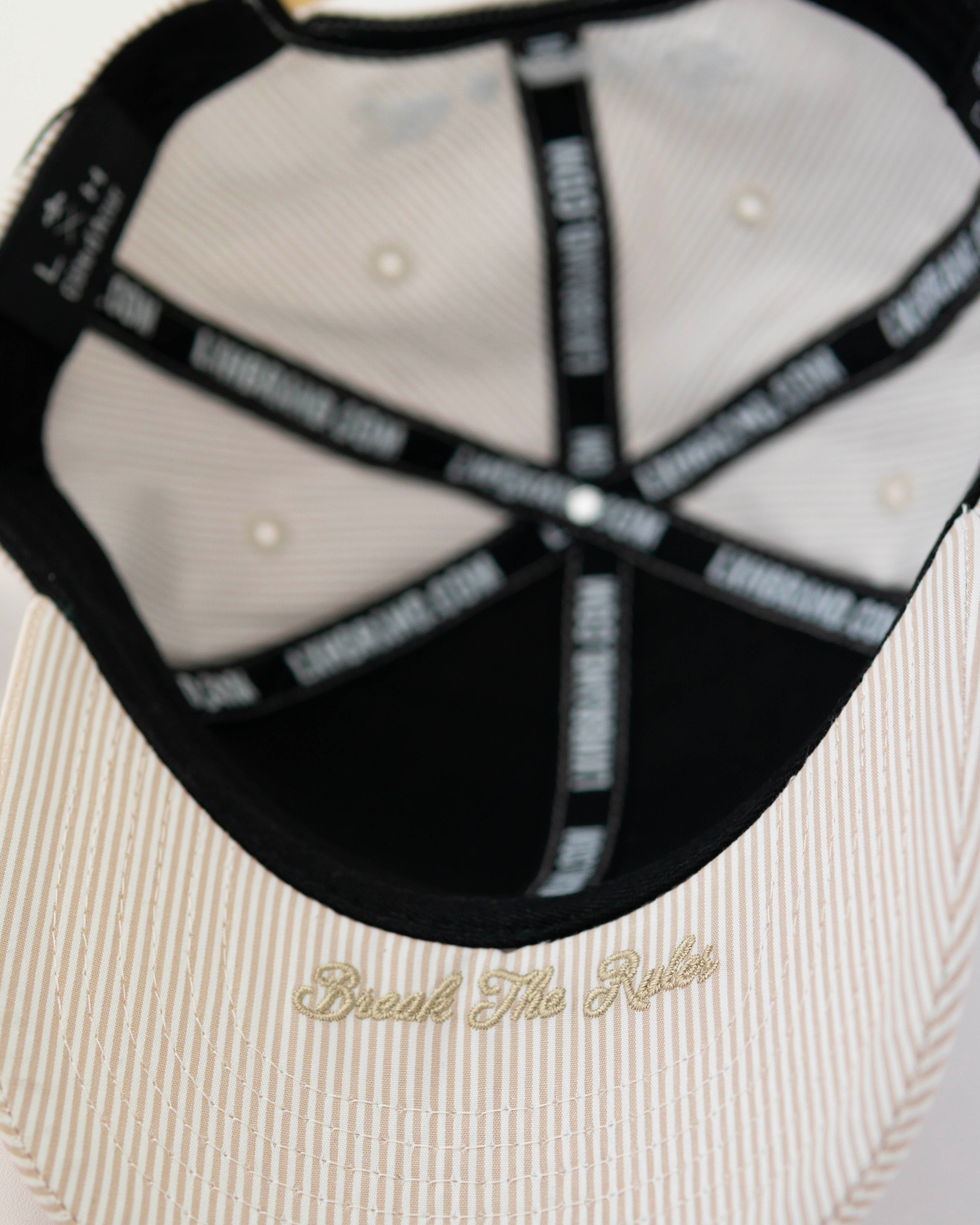 Intérieur d'une casquette enfant rayures beige blanc avec inscription dorée 'Break The Rules'