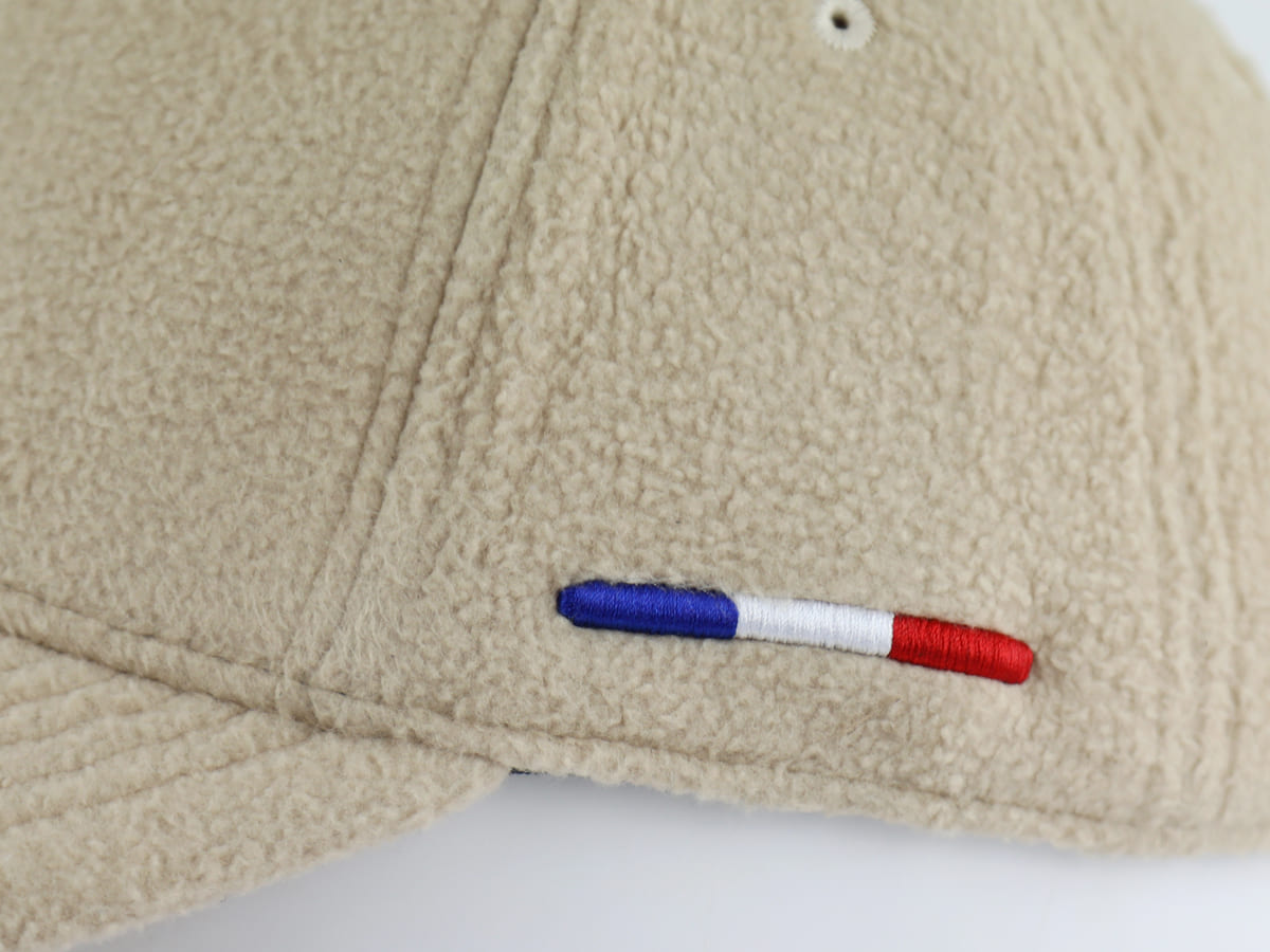 Détail du petit drapeau français bleu blanc rouge brodé sur la couture latérale de la casquette polaire beige Héritage LXH