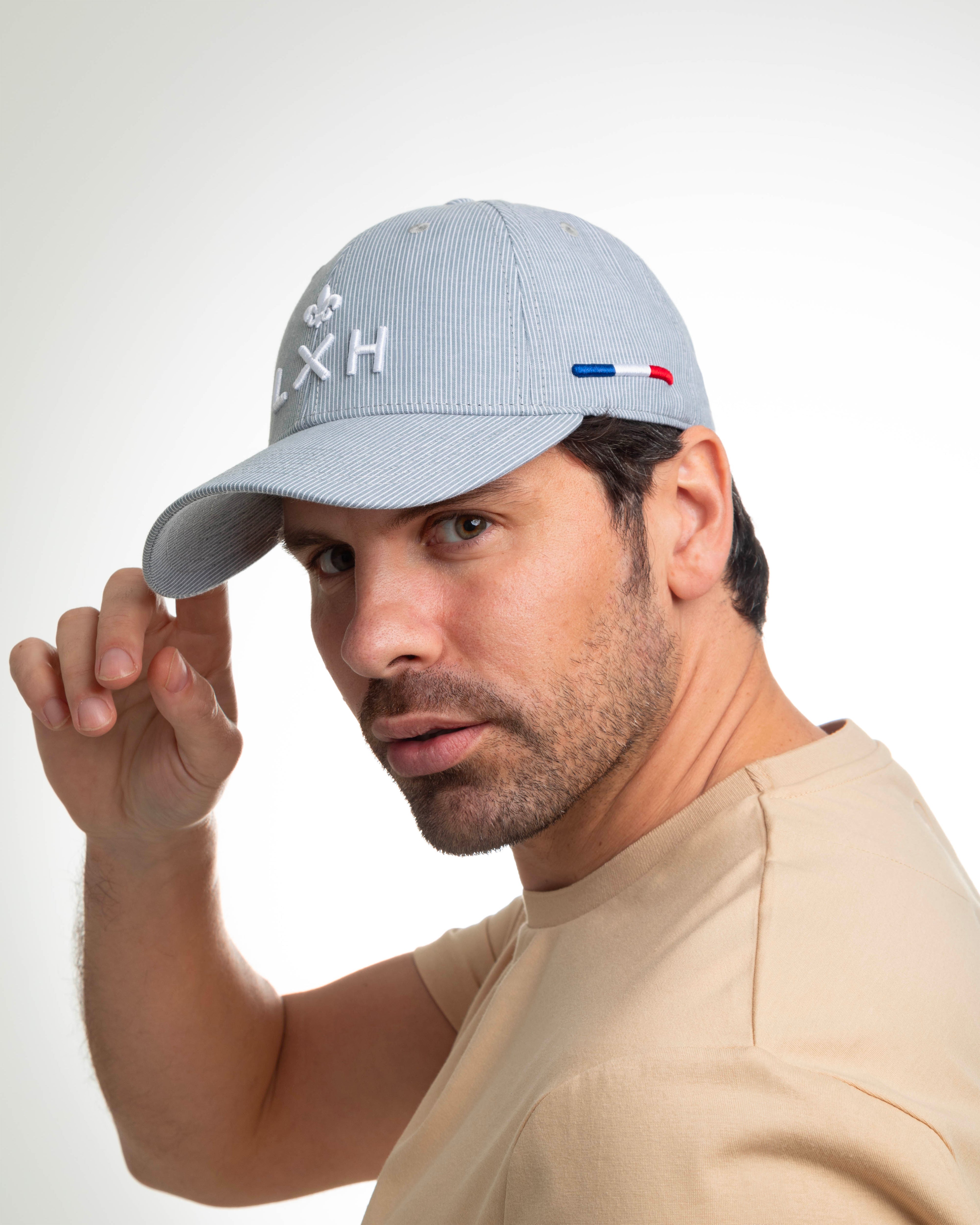 Homme portant une casquette rayée bleu gris de la marque LXH avec logo brodé