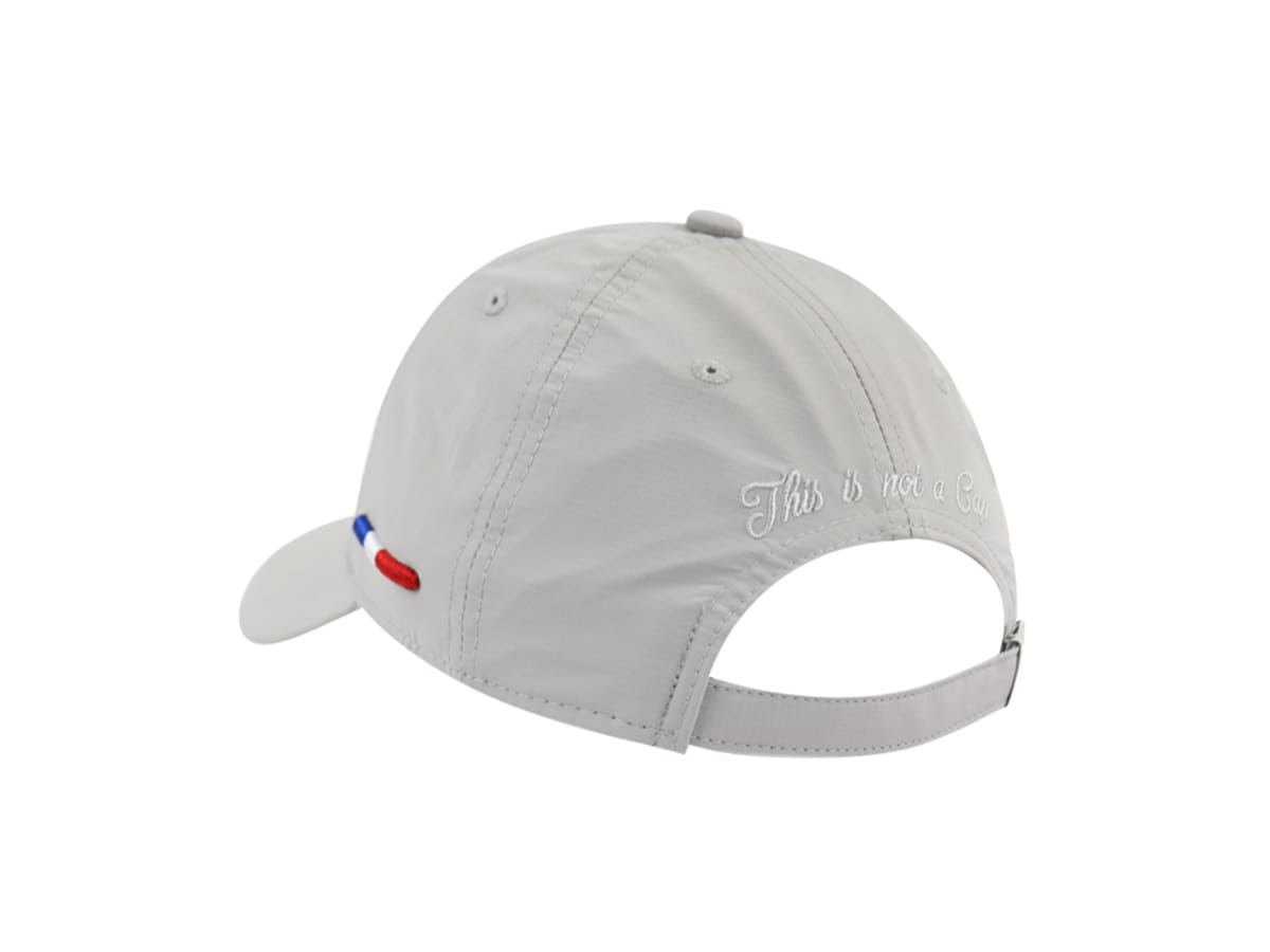 Trois quarts arrière LXH nylon gris clair, broderie cursive blanche This is not a Cap, sangle réglable, drapeau